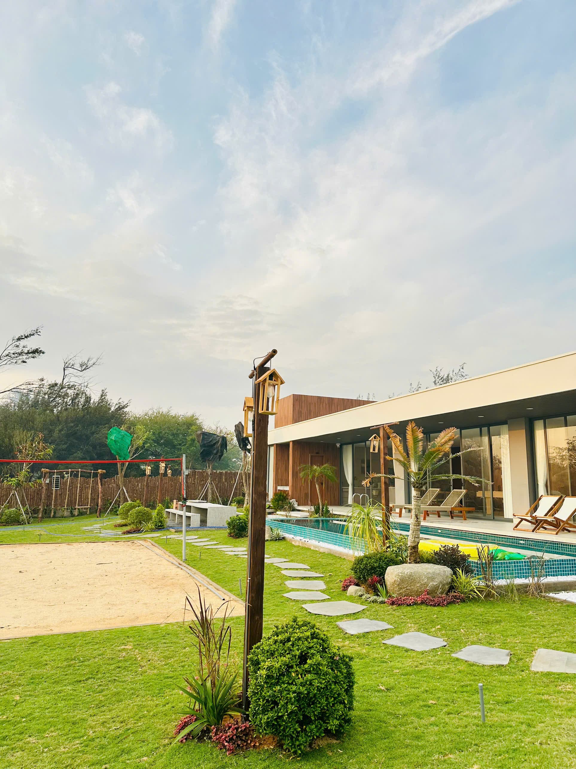 Toàn cảnh villa — sân cát, hồ bơi, vườn xanh